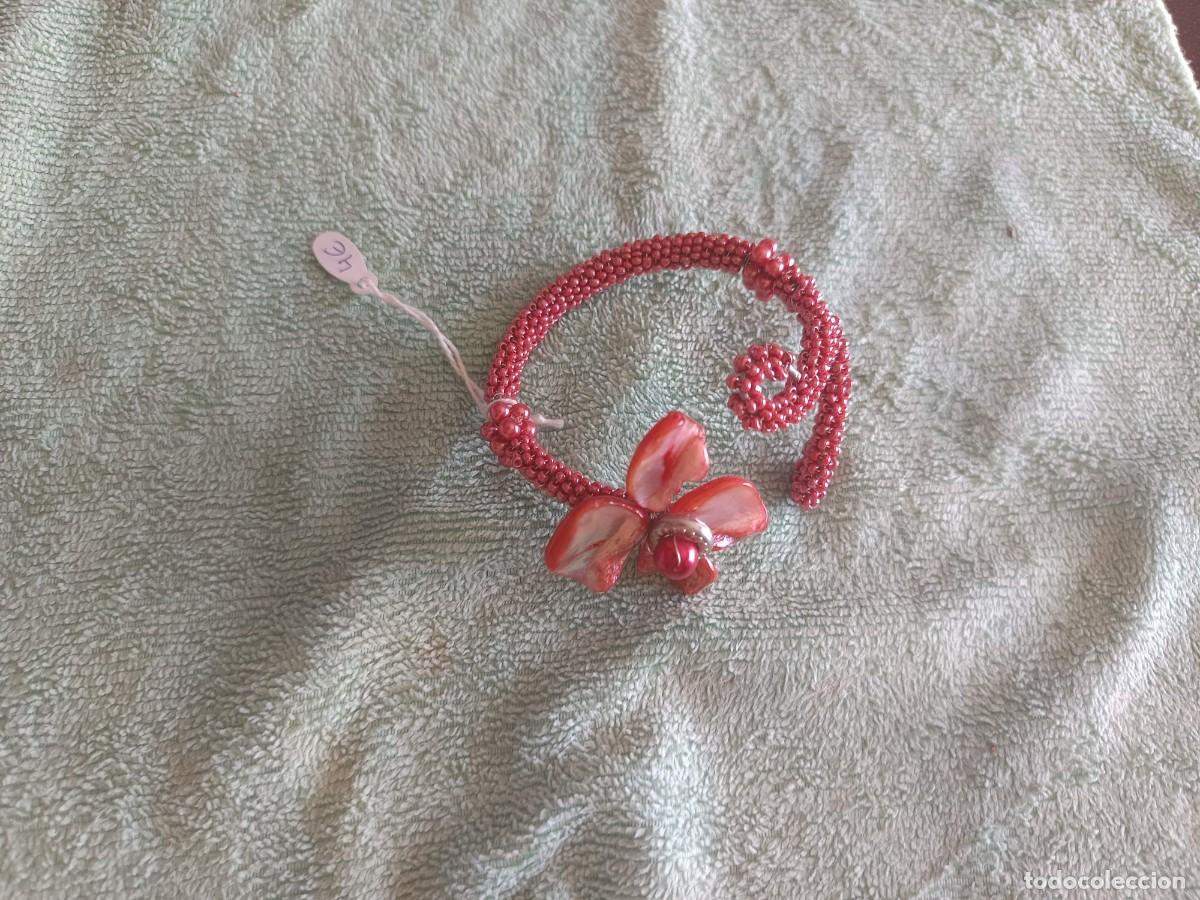 Joyeria: Brazalete artesanal de abalorios rojos en espiral destaca por su delicado detalle floral