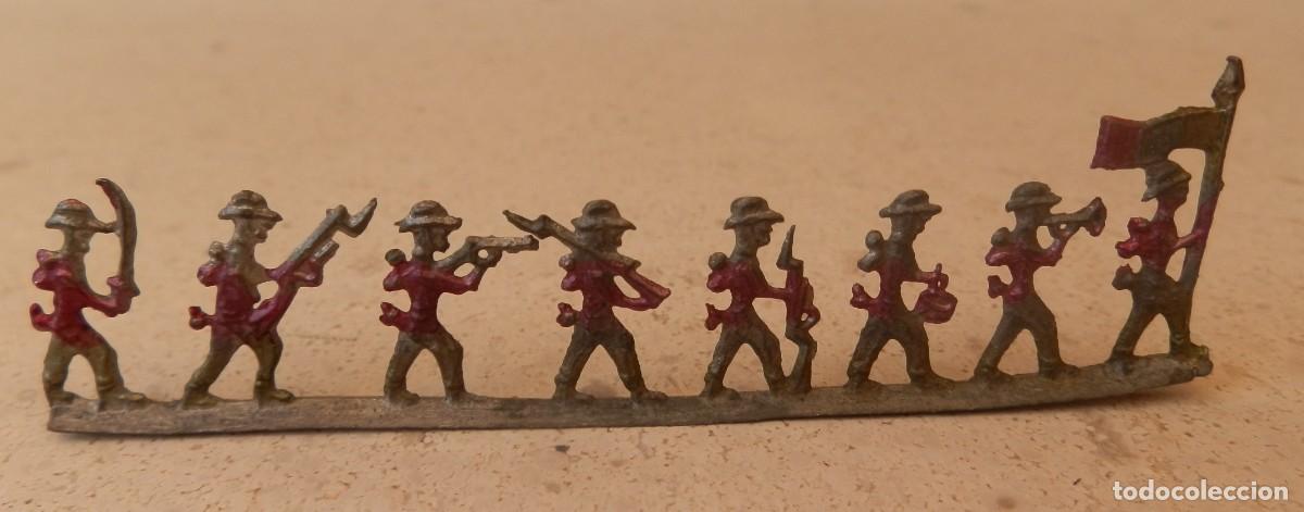 Jogos Antigos: 8 antiguos figuras de soldados planas de plomo pintadas a mano, unidas por una peana com&uacute;n.