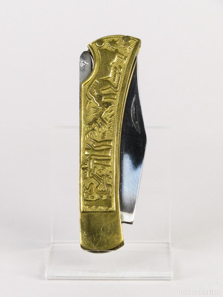 Militaria: Navaja pakistan&iacute; con hoja de acero y cachas de lat&oacute;n con relieves de caza siglo XX
