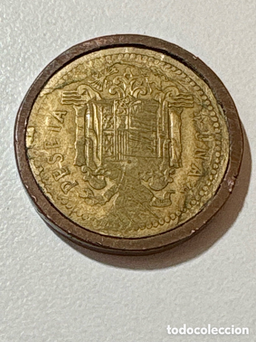 Monedas Franco: Moneda de 1 Peseta de Juan Carlos I (A&ntilde;o 1975) engastada en cerco de m&aacute;quina recreativa.