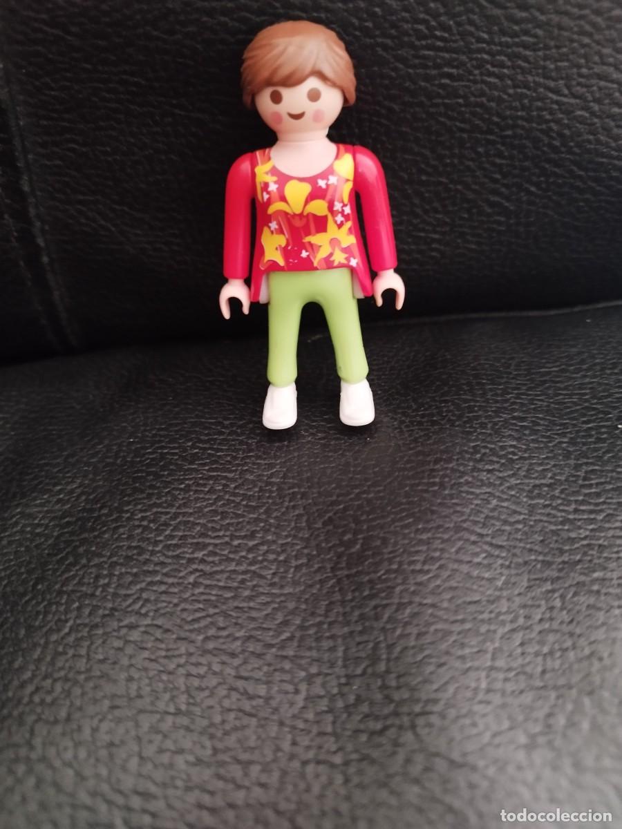 Playmobil: Figura Playmobil de chica con pelo casta&ntilde;o coleta con coletero, camiseta roja flores amarillas.