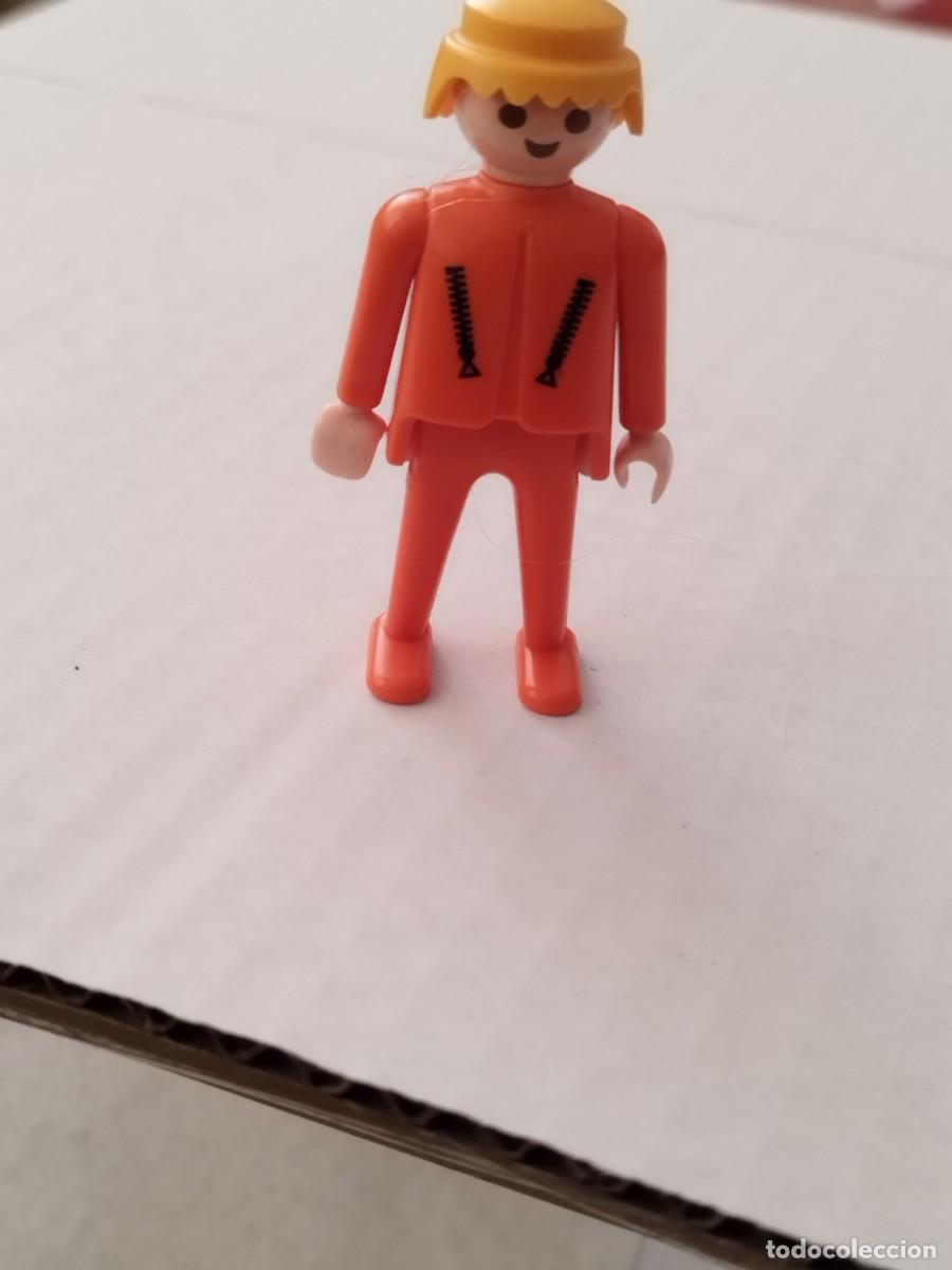 Playmobil: Figura Playmobil geobra, chico rubio color naranja con cremalleras en los bolsillos.