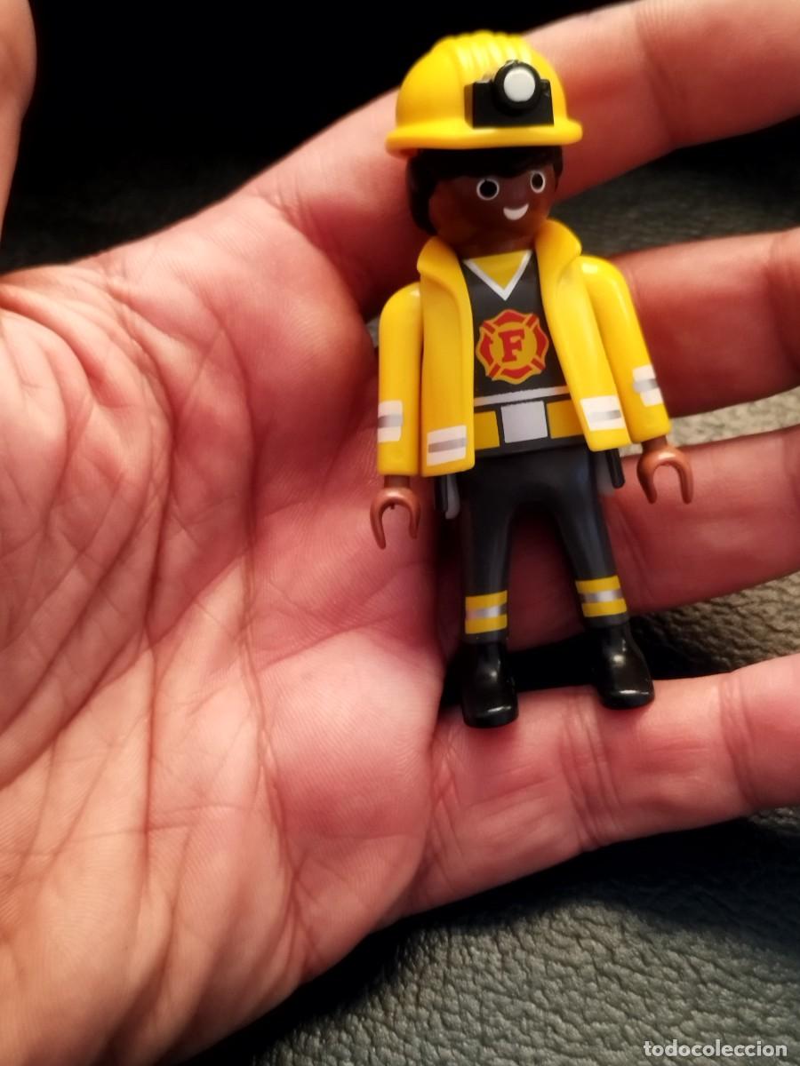 Playmobil: Figura Playmobil, bombero negro con chaqueta ign&iacute;fuga y casco de color amarillo con frontal, luz.