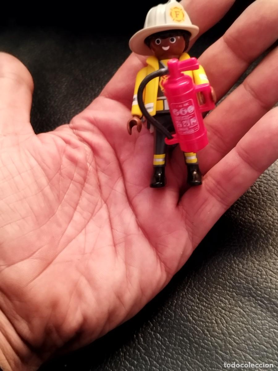 Playmobil: Figura Playmobil, bombero negro con chaqueta inifuga color amarillo y extintor.