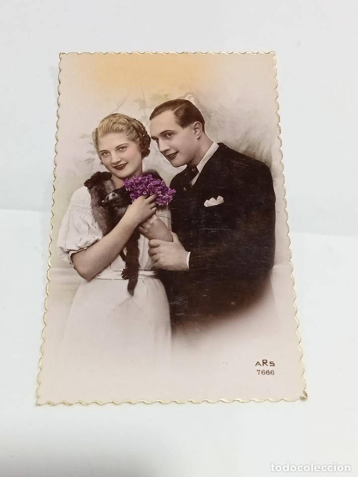 Cartoline: TARJETA POSTAL. PAREJA DE ENAMORADOS VESTIDOSE &Eacute;POCA CON VIS&Oacute;N Y RAMILLETE DE FLORES MORADAS