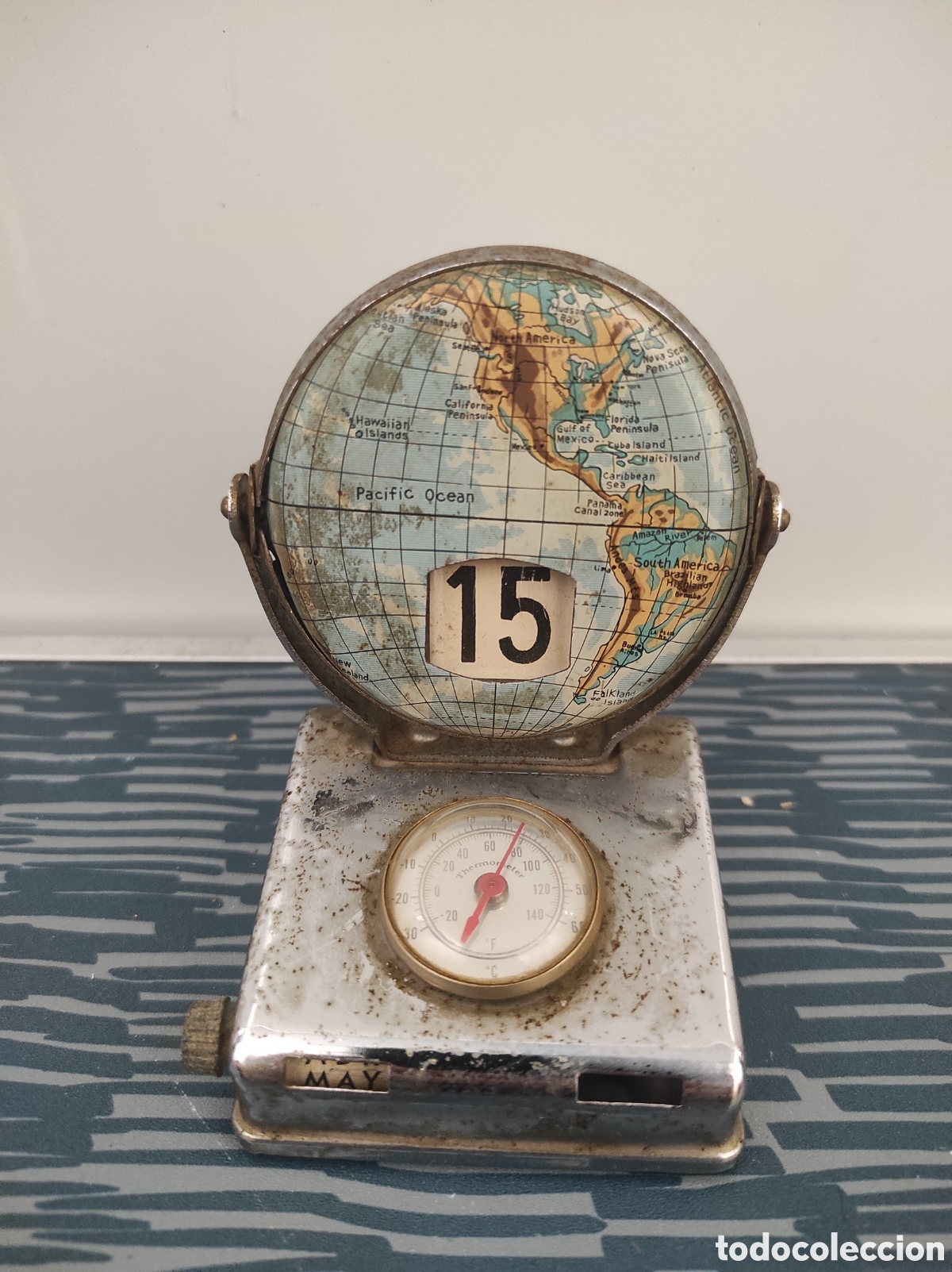 Relojes de carga manual: Calendario con term&oacute;metro de sobremesa de metal con globo terr&aacute;queo . A&ntilde;os 60