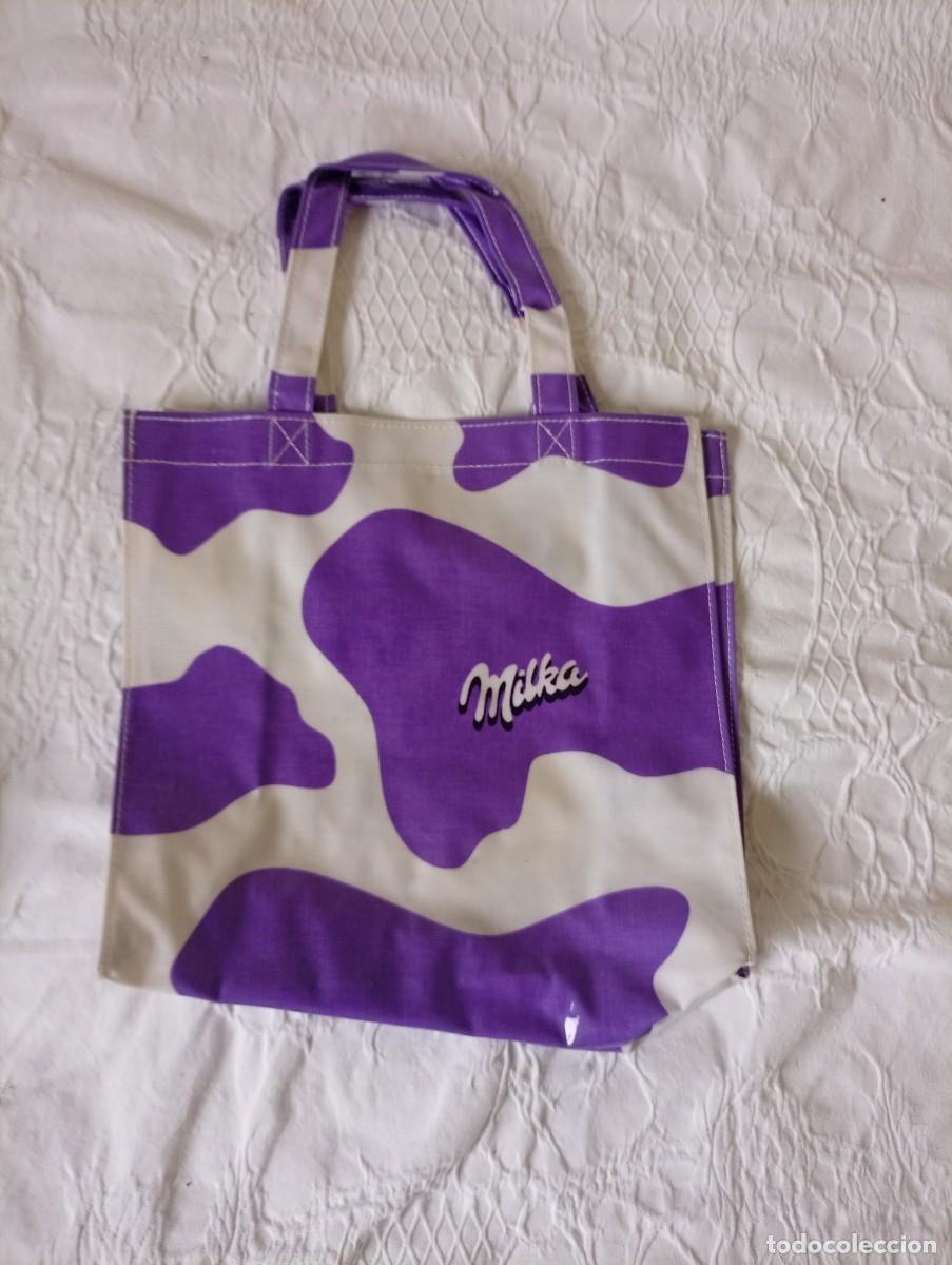 Segunda mano: Peque&ntilde;a bolsa con el distintivo dise&ntilde;o de manchas de vaca en morado y blanco.- Logo de Milka en el f