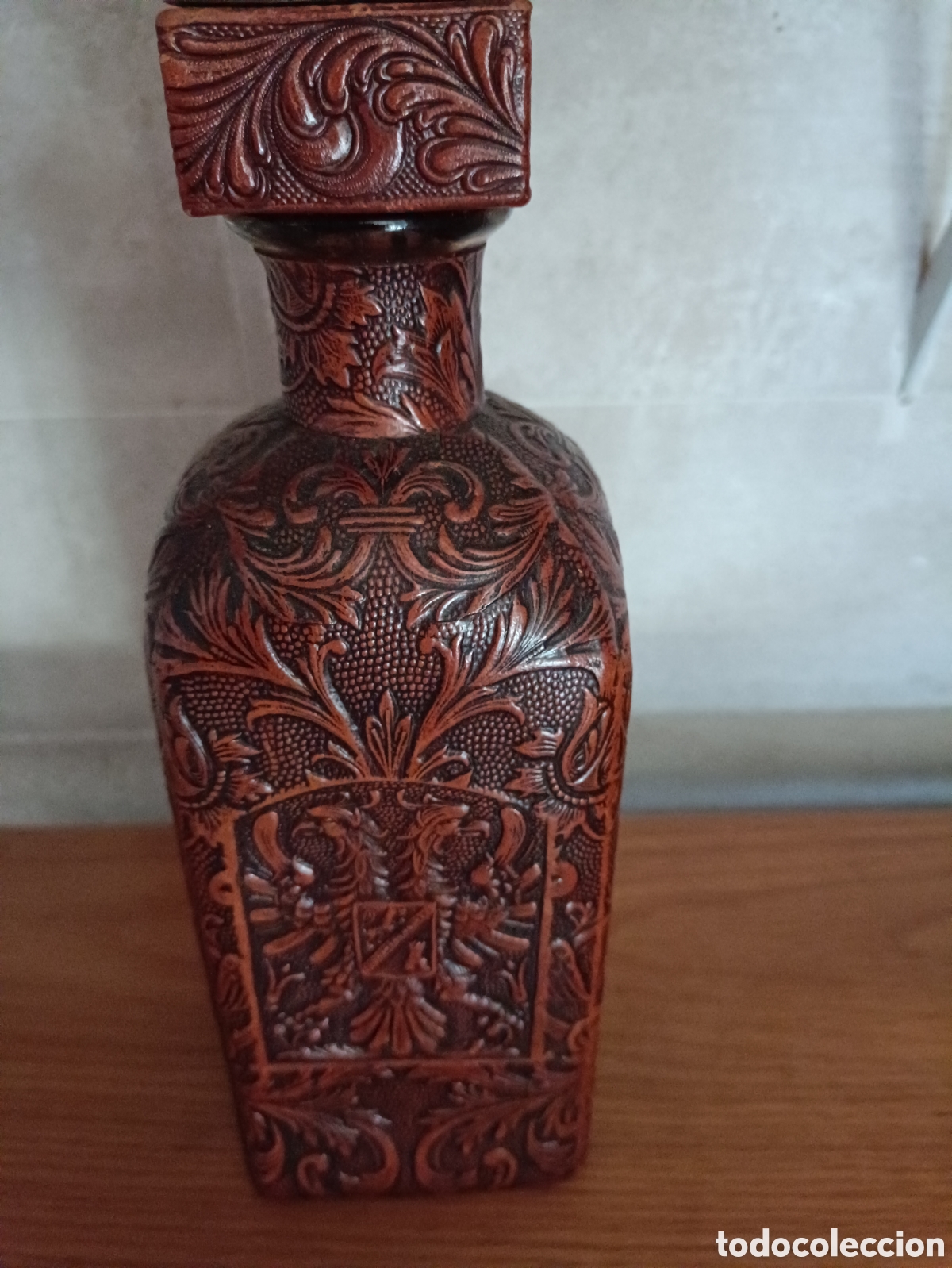 Segunda mano: Botella o licorera antigua forrada en cuero repujado con tap&oacute;n de dise&ntilde;o floral y her&aacute;ldica
