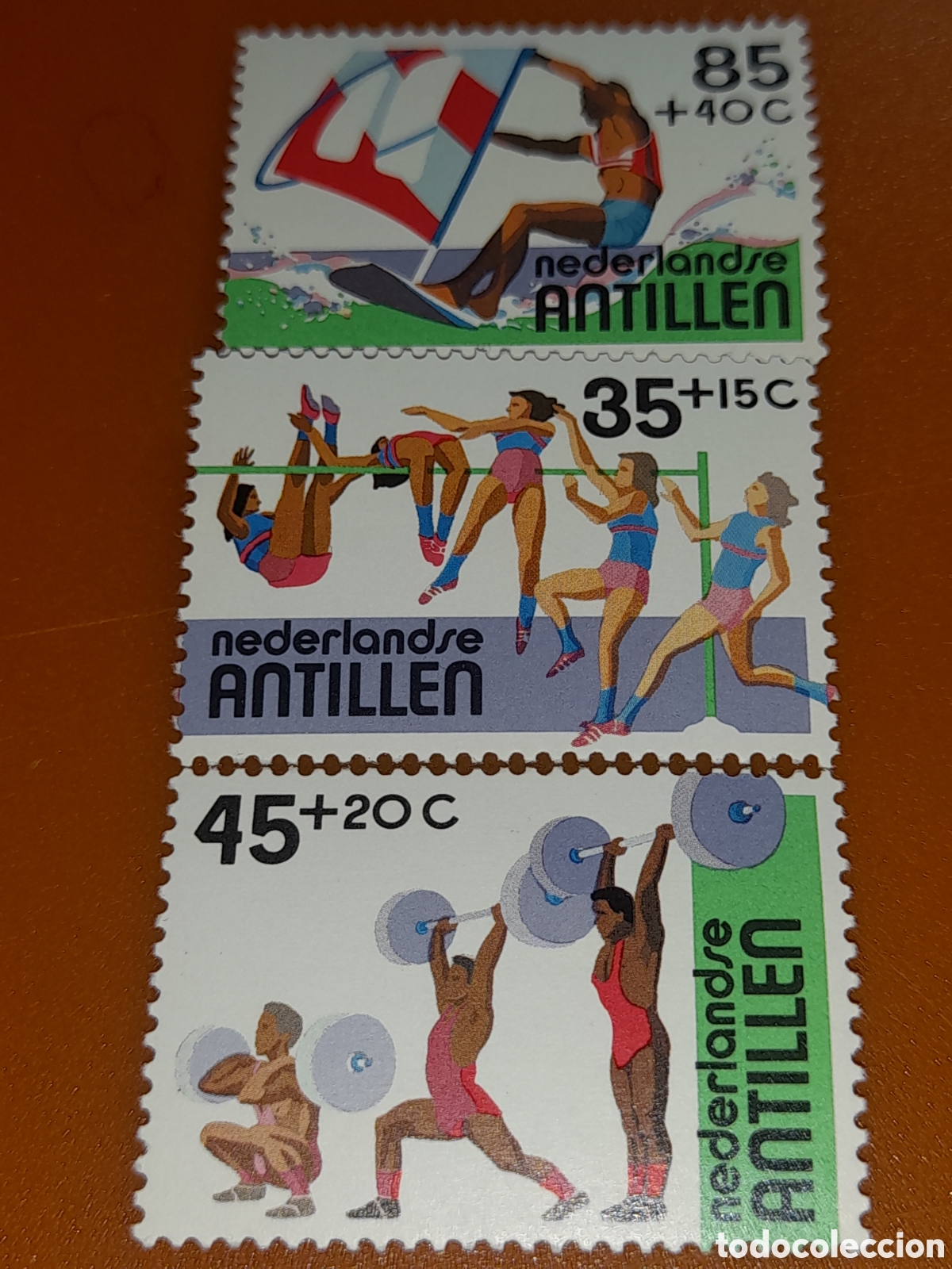 Sellos: Sello Antillas Holandesas nuevo 1983. Deportes. Juegos. Surf. Halterofilia. Salto altura. Atletas.