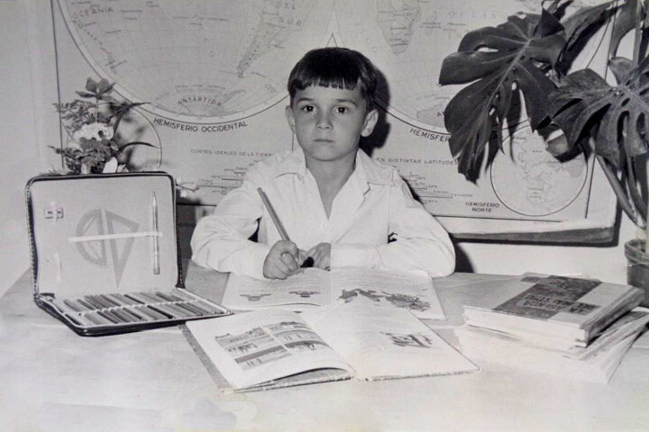 Alumno aplicado con libor escolar plumier y mapa al fondo