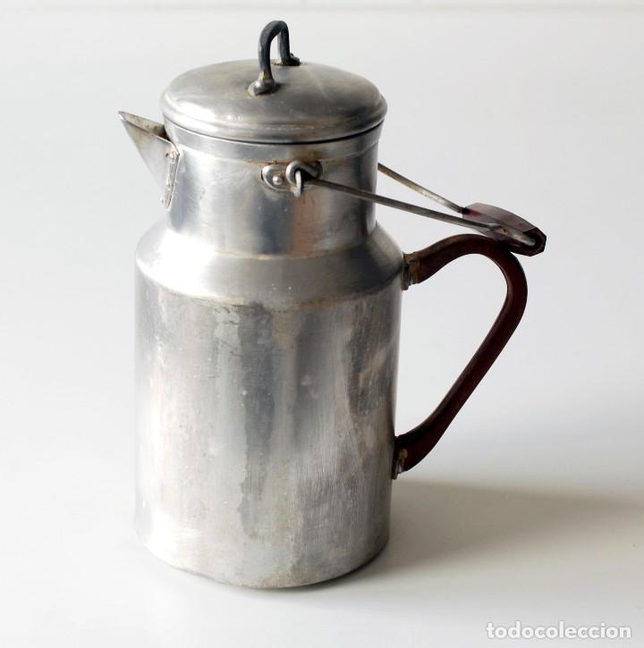 Vintage: Antigua aceitera de aluminio, con asa y mango de baquelita color rojo. Mide 25 cm de alto y 13 cm.